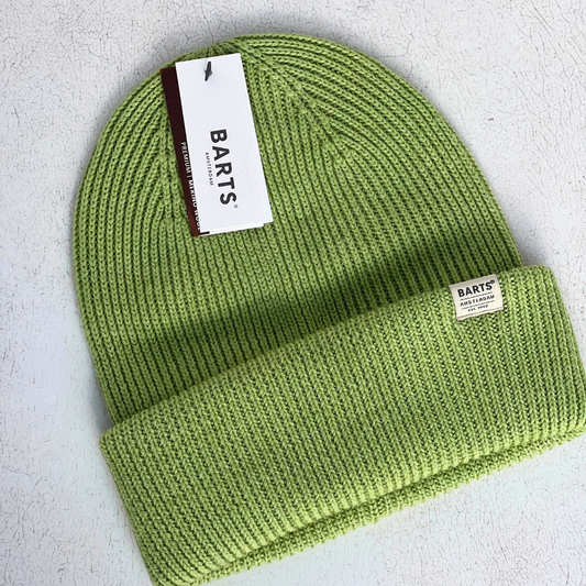 A lime green ribbed knit beanie hat with a folded cuff, featuring a white BARTS brand hangtag and a small sewn-on brand label, laid flat on a textured light gray background.